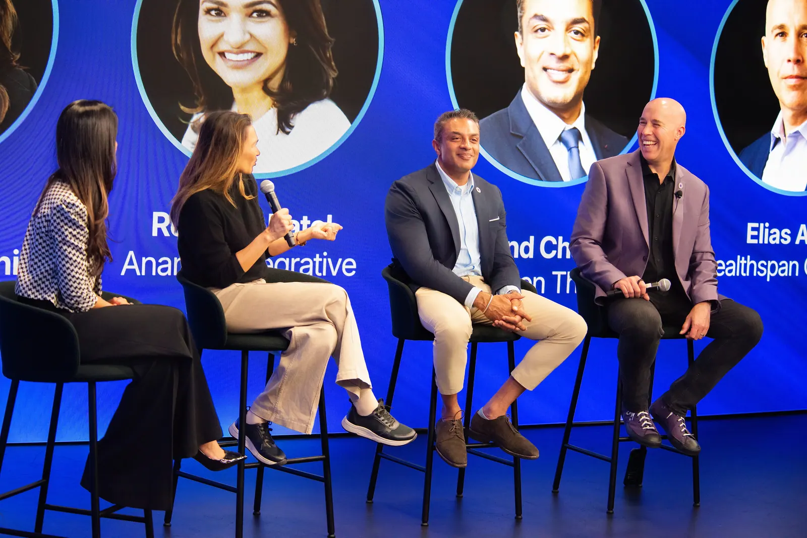 Hosts on the Healthspan Summit stage between glowing purple screens